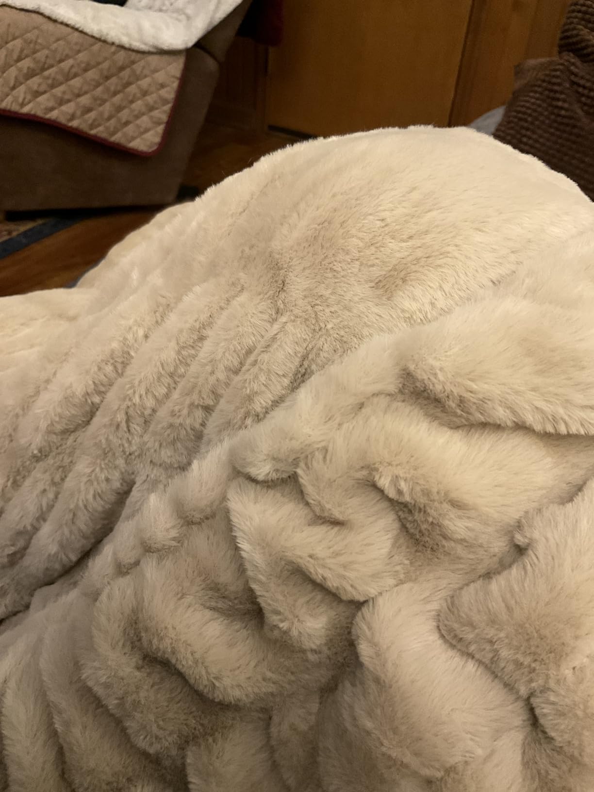 Close-up of a soft beige Aruva SereneWeave throw keeping someone's arms and legs warm in their recliner