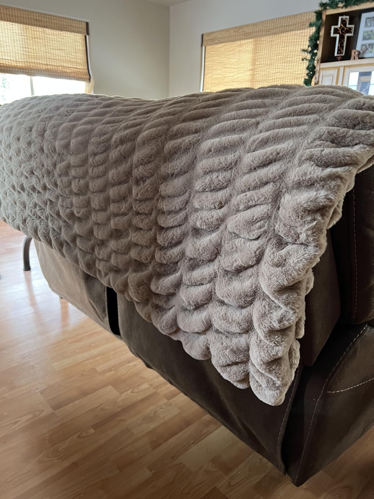 Customer photo showing textured beige Aruva SereneWeave blanket draped over a sofa in a living room setting.
